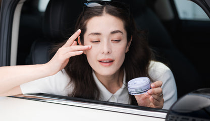 Woman applying bakuchiol niacinamide cream to her face in a car