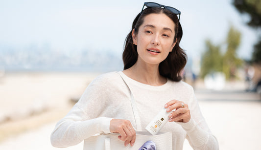 Woman holding a tote bag with a product on a blurred outdoor background
