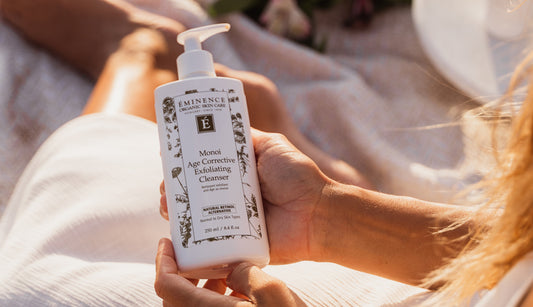 Person holding a bottle of Eminence Organics cleanser with a blurred background